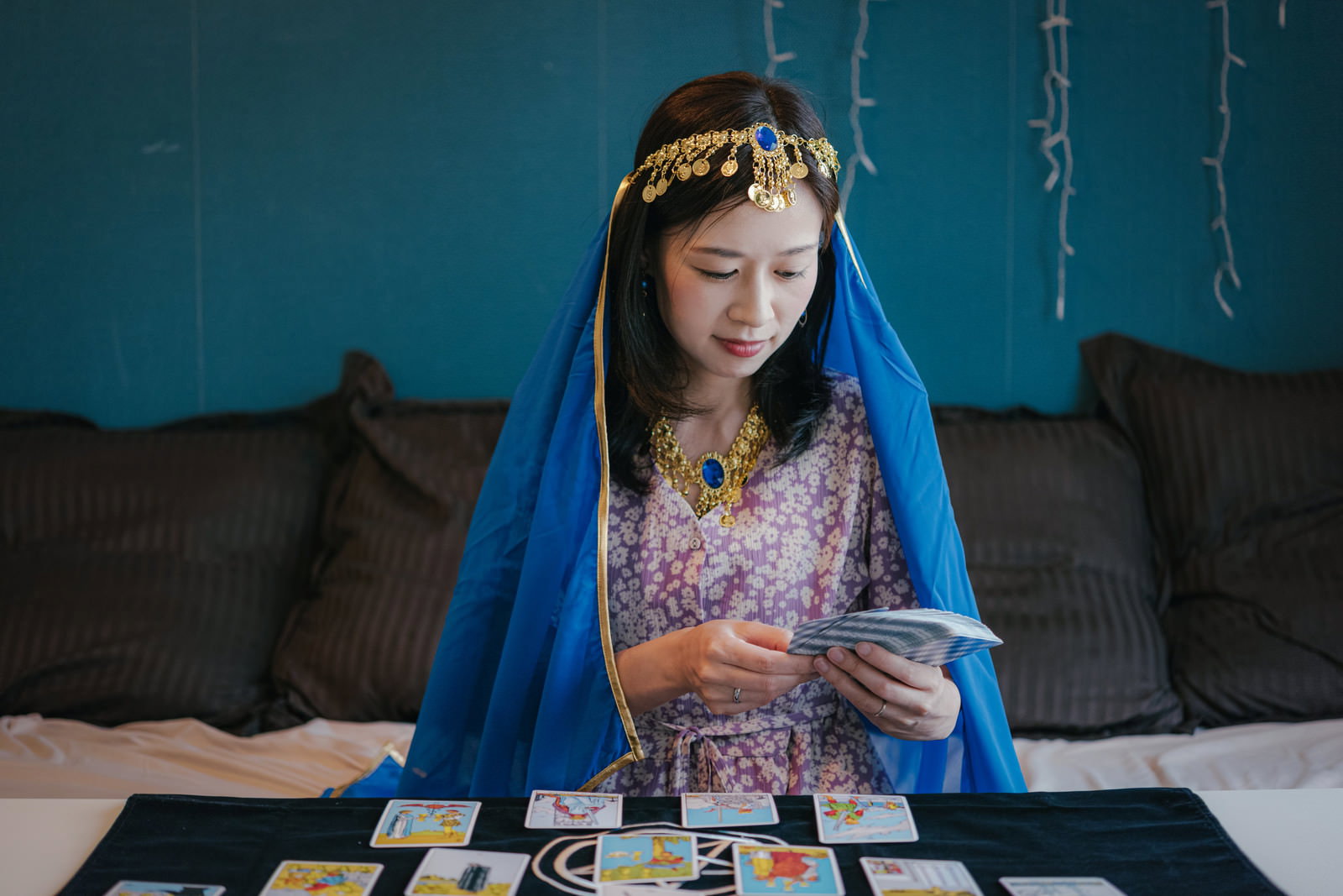 青いベールを被った女性がタロットカードで占いをしている様子