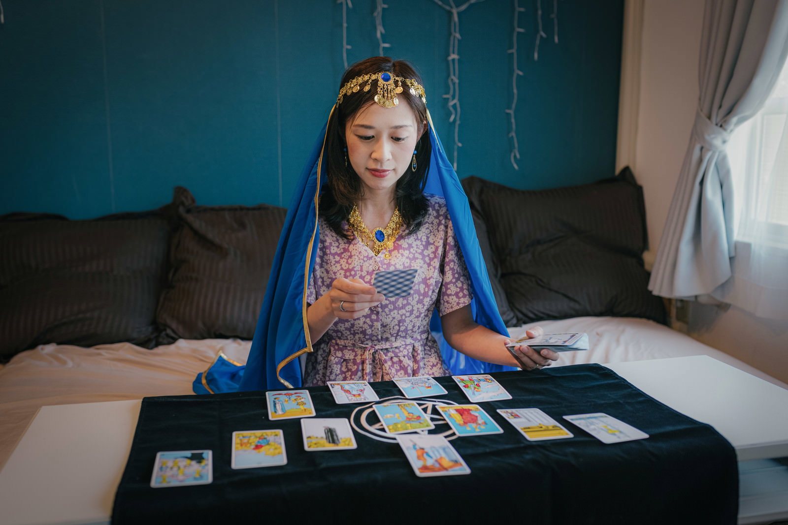 青い髪の女性がタロットカードを使って占いをしている写真