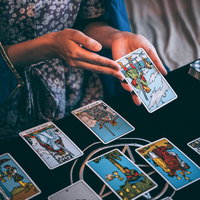 黒いテーブルでタロットカードを広げて運勢を占う女性の写真