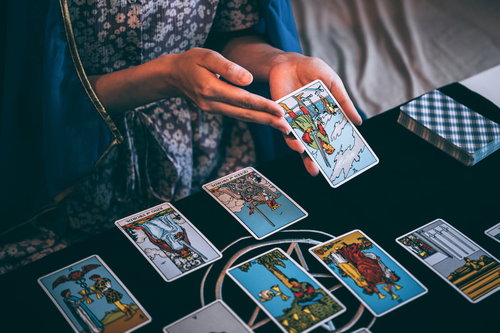 黒いテーブルでタロットカードを広げて運勢を占う女性