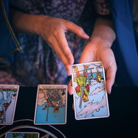 タロットカードで選ばれた1枚（ソードの5）を手に持つ女性の写真