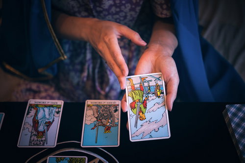 タロットカードで選ばれた1枚（ソードの5）を手に持つ女性