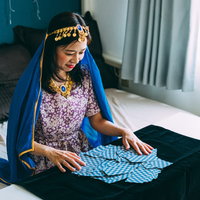 紫のドレスを着たタロットカードをシャッフルする女性占い師の写真
