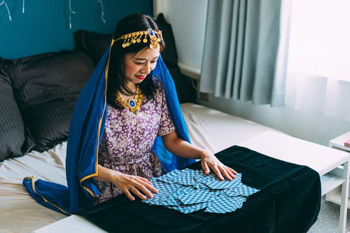 紫のドレスを着たタロットカードをシャッフルする女性占い師