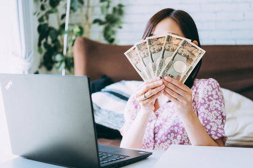 在宅ワークで得た報酬、一万円札を手に持つ女性