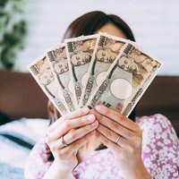 副収入を自慢する主婦が一万円札を手に持つの写真