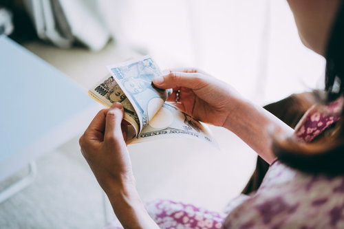 在宅ワークの副業で得た報酬を数える女性の手元