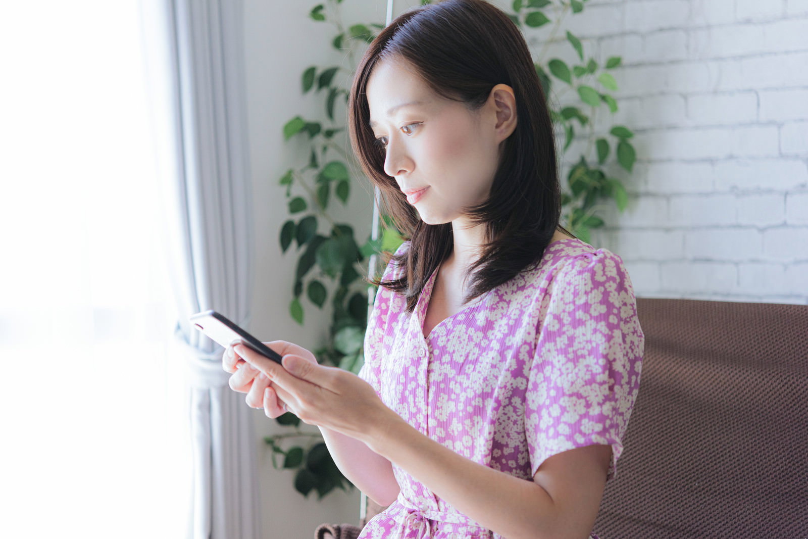 ピンクの服を着た女性がスマートフォンを操作している様子