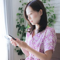 スマホを使って取引を行う在宅ワーク中の女性の写真