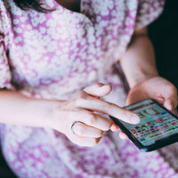 スマホで副業関連の情報サイトを見る女性の手元の写真