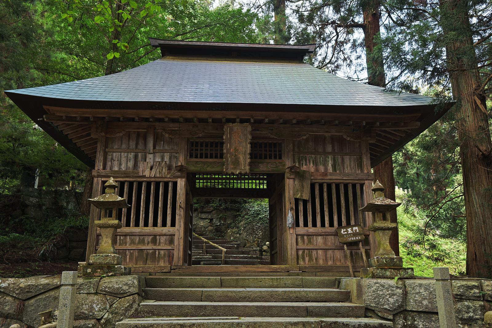 杉の木に囲まれた東堂山満福寺の古い木造の仁王門