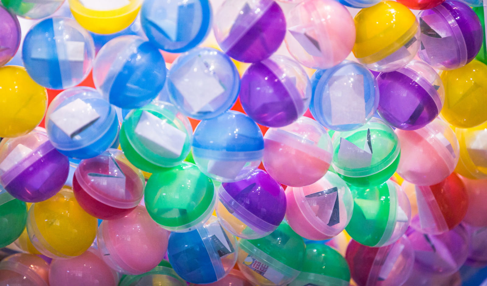 A large pile of colorful plastic gacha capsules stacked on top of each other