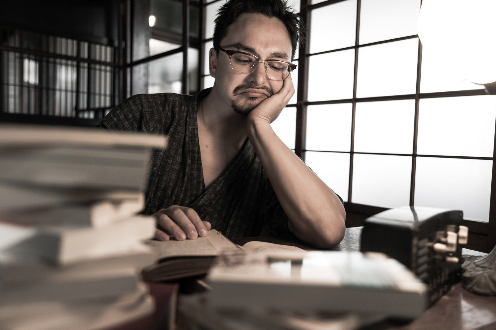 古民家の書斎で甚平を着た外国人男性が文献を読みながら考えている［モデル：Max_Ezaki］