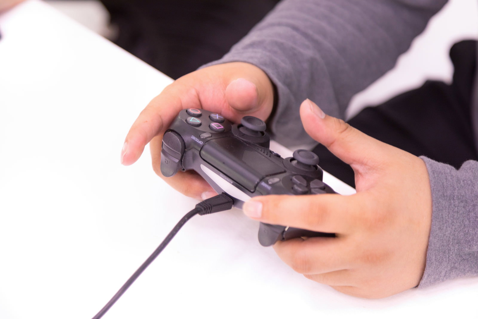 黒いゲームコントローラーを両手で操作している手元［モデル：段田隼人］