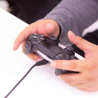 ゲームコントローラーを両手でしっかり握ってプレイする男性の手元の写真