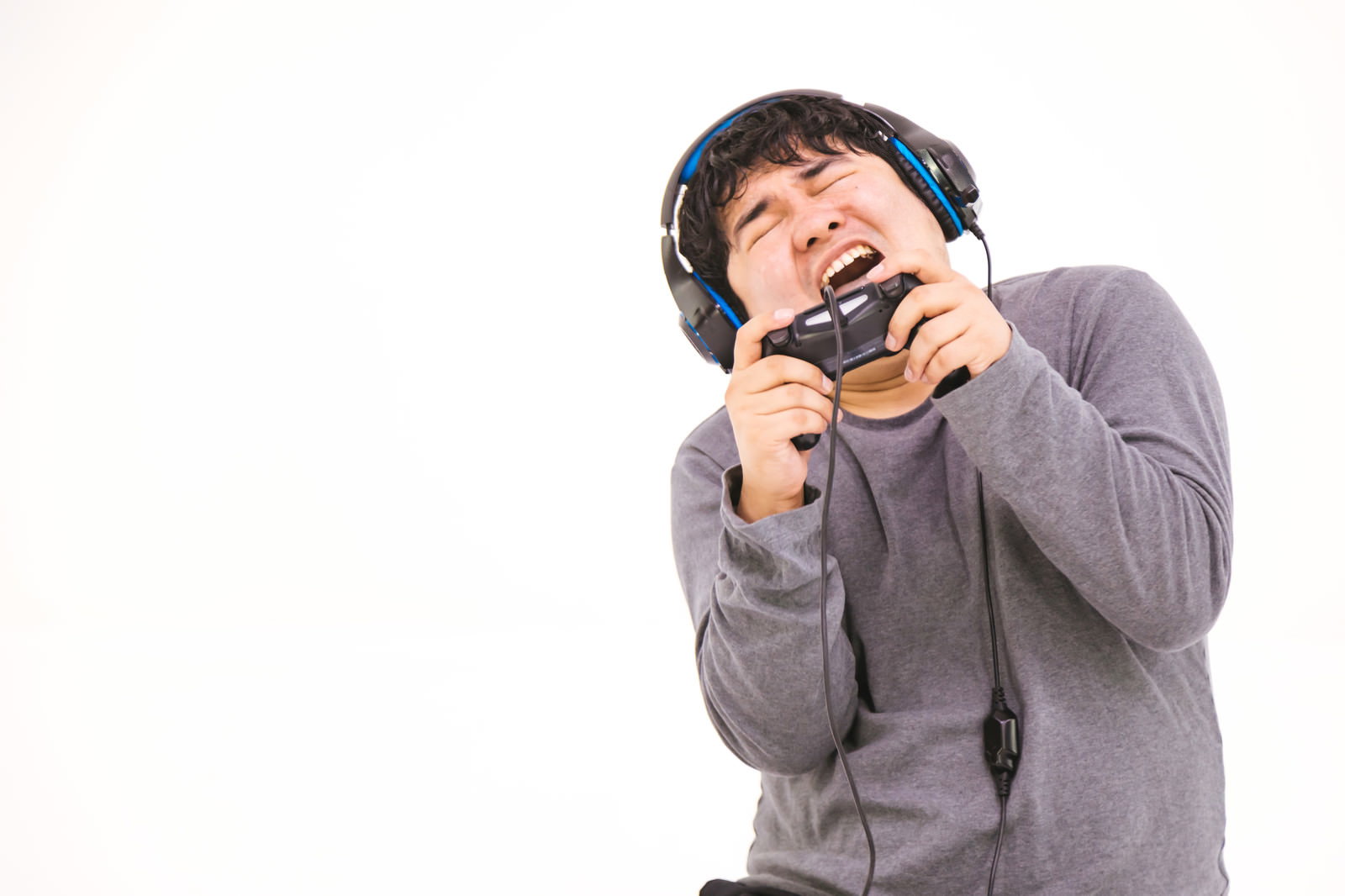 ヘッドセットを付けてコントローラーでゲームをプレイする男性［モデル：段田隼人］