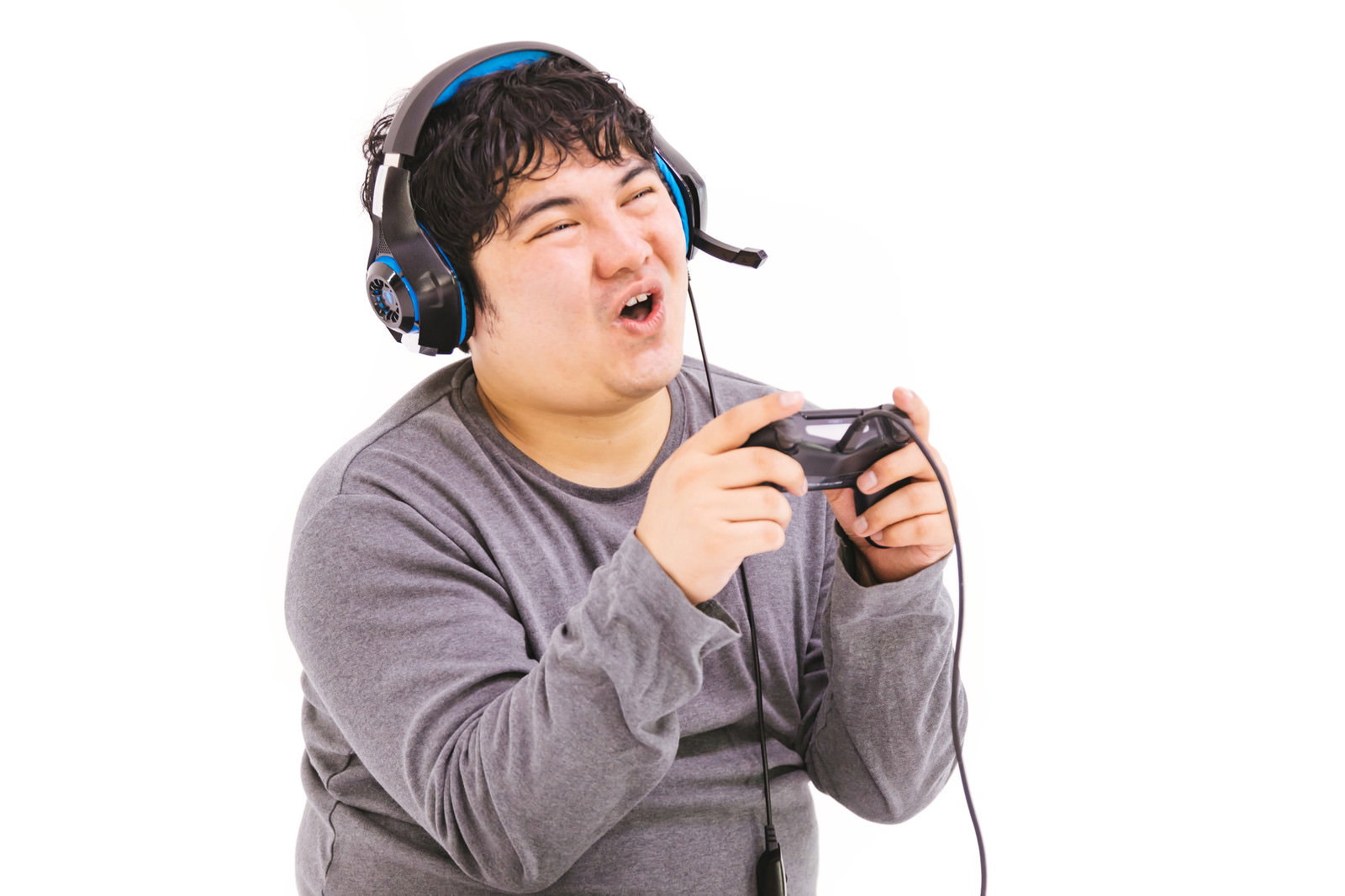 ゲームコントローラーを握って驚いた表情を見せるヘッドセット装着の男性［モデル：段田隼人］