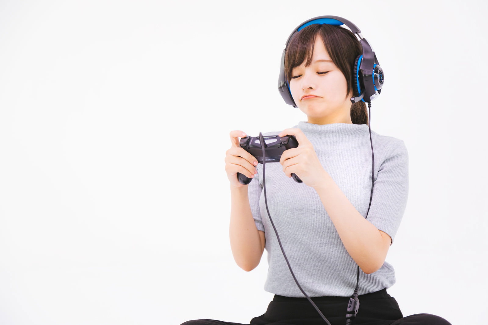 黒いゲームコントローラーを持ちヘッドセットを装着した女性［モデル：千歳］