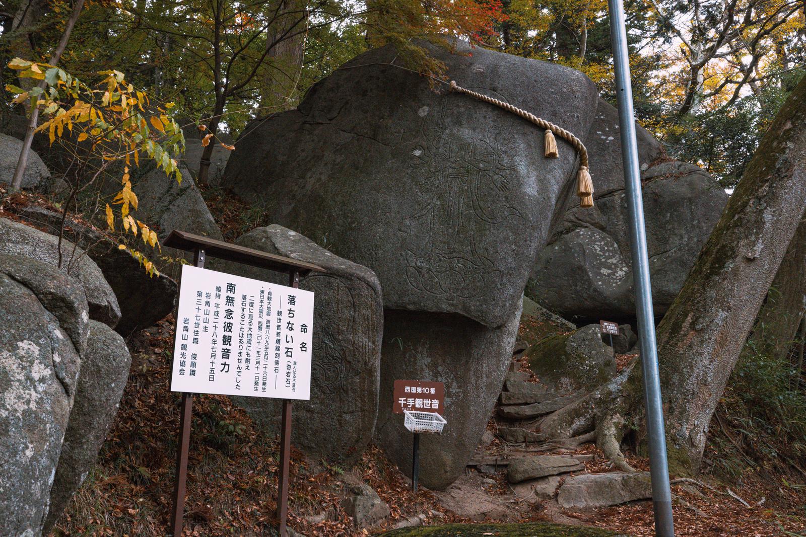 苔むした巨石に綱を巻き、秋の樹木に囲まれた岩角寺の境内風景