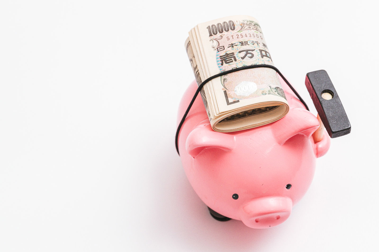ピンク色の豚の貯金箱から飛び出した一万円札と横に置かれた札束