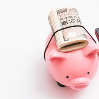 豚の貯金箱に入らなかった一万円札と札束を積み重ねたの写真