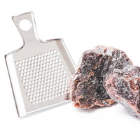 白いおろし金とピンク色の岩塩の結晶、調理器具と食材の写真