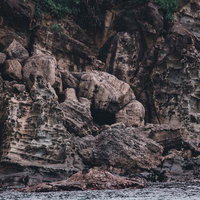 海に削られた褐色の崖と地層の断面、海岸侵食による岩肌の露出の写真