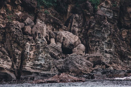 海に削られた褐色の崖と地層の断面、海岸侵食による岩肌の露出