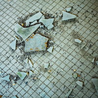 汚れたタイルと飛び散るガラス片の写真