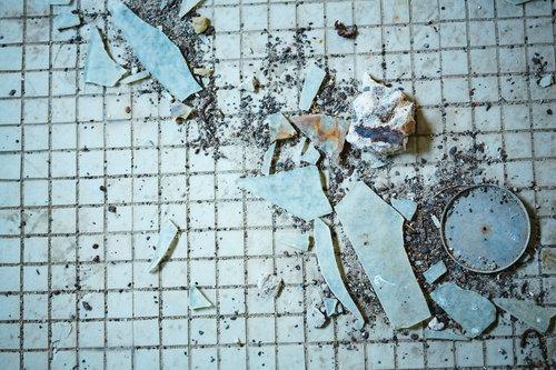 古びたタイルとガラス片が散乱する廃墟の床