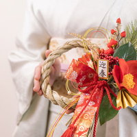 迎春の正月飾りを両手で持った着物姿の女性の写真