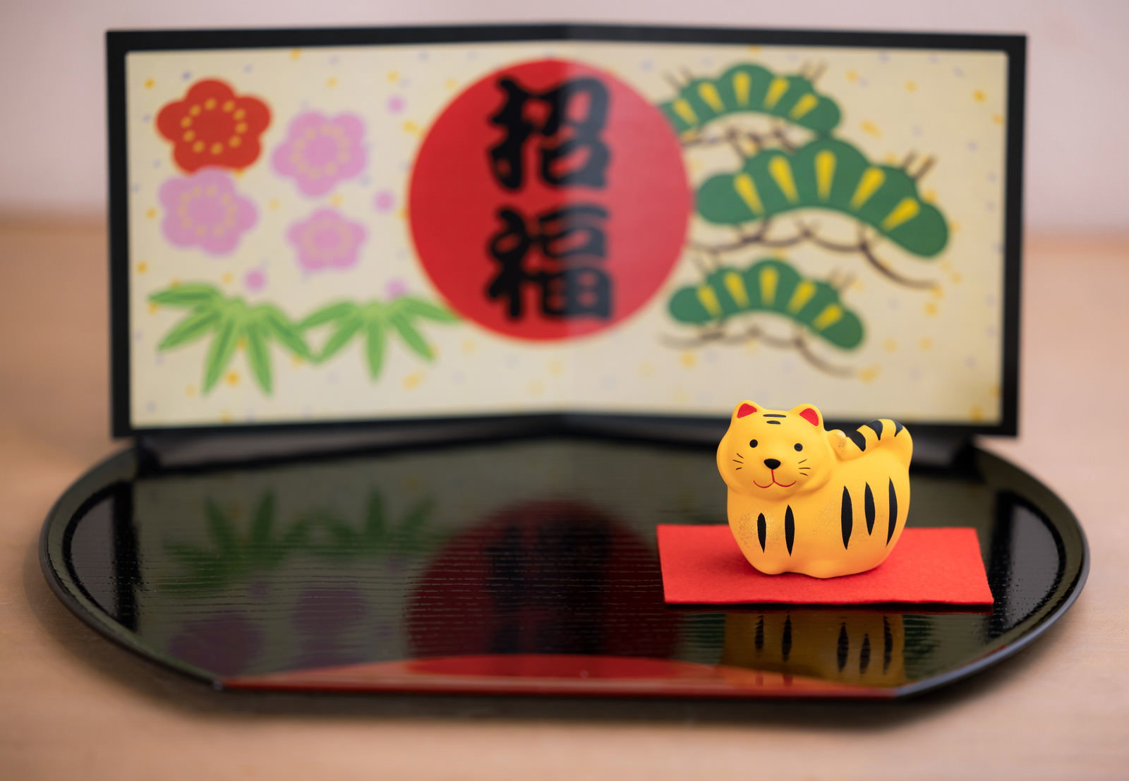 黒いお盆の上に虎の置物と招福の絵馬風飾り板