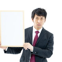 白いフリップを持つスーツ姿の男性会社員がプレゼンテーション中の写真