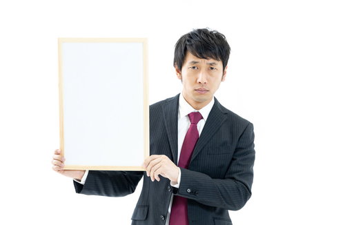 白いフリップを持つスーツ姿の男性会社員がプレゼンテーション中