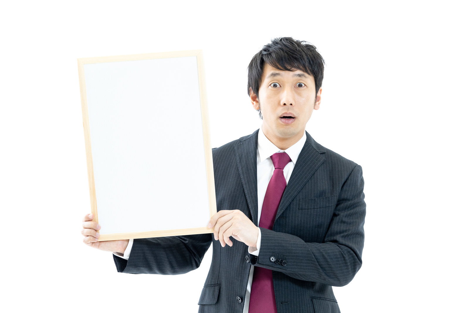 ホワイトボードを持って驚いた表情をするスーツ姿の男性［モデル：大川竜弥］