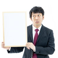 クイズの答えが気になるスーツ姿の司会者がホワイトボードを持つの写真