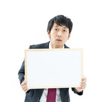 フリップで指示を出す不安げなディレクター男性の写真