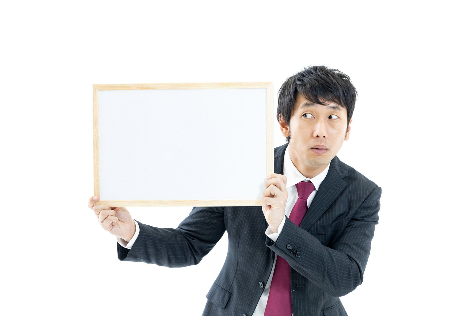 白いホワイトボードを持ち、不安そうな表情のスーツ姿の男性［モデル：大川竜弥］