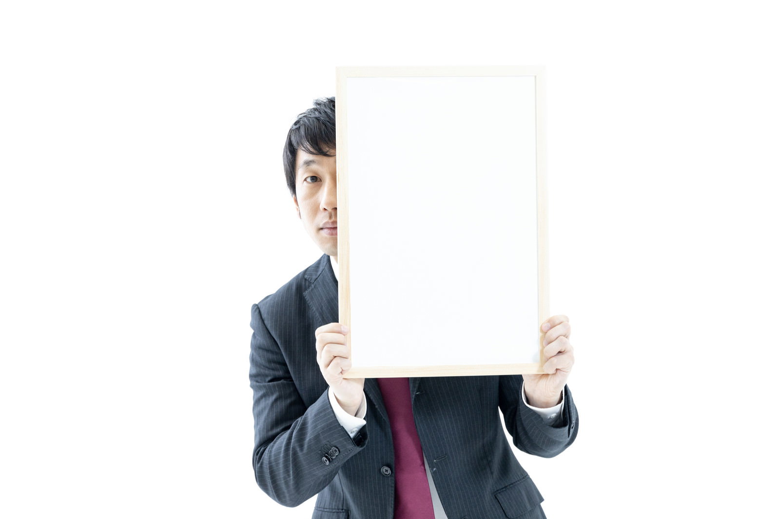 白いホワイトボードの横から紺色のスーツを着た男性が顔を出している［モデル：大川竜弥］