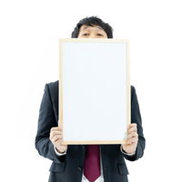 正解の反応が気になるスーツ姿の司会者がフリップを持つの写真