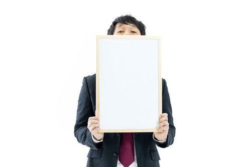 正解の反応が気になるスーツ姿の司会者がフリップを持つ