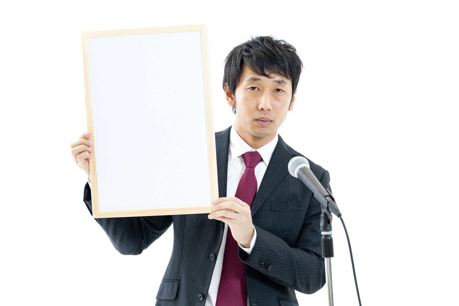 赤いネクタイを締めたスーツ姿の男性が白いフリップボードを掲げている［モデル：大川竜弥］