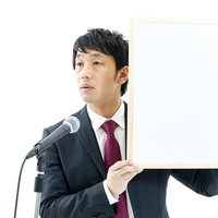 記者の質問に答える政治家がホワイトボードを掲げるの写真