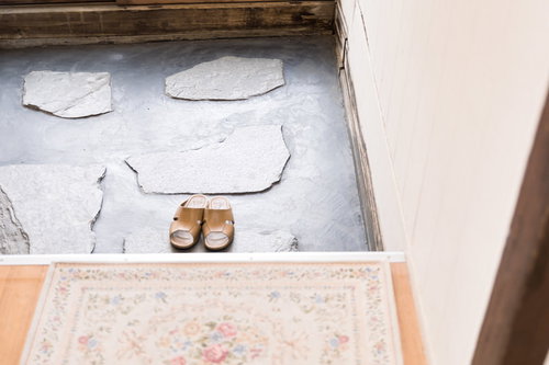 昭和の古民家の玄関に置かれた茶色のサンダルと石畳