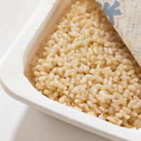 白い容器の玄米レトルト、麻袋と一緒に配置された健康食品の写真