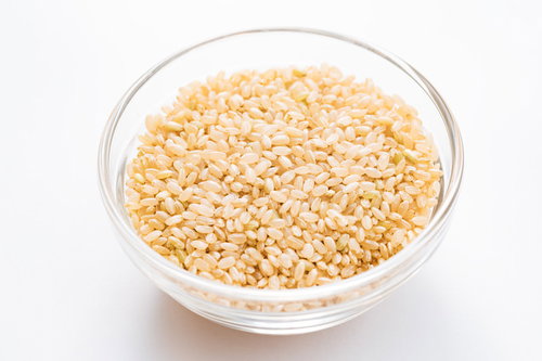 透明ボウルに盛られた玄米粒 - 健康食品の食材