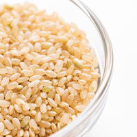 ガラス容器に入った玄米粒と穀物の食材。健康食として注目される玄米の写真