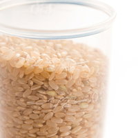 透明な計量カップに入った玄米の粒と計量風景の写真