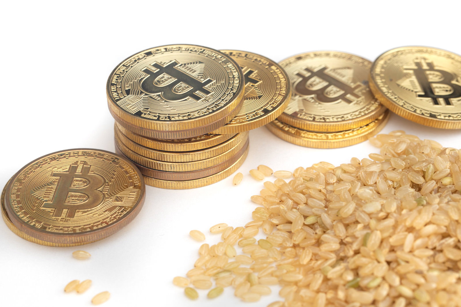 金色のビットコインコインと玄米粒が並んで配置された写真