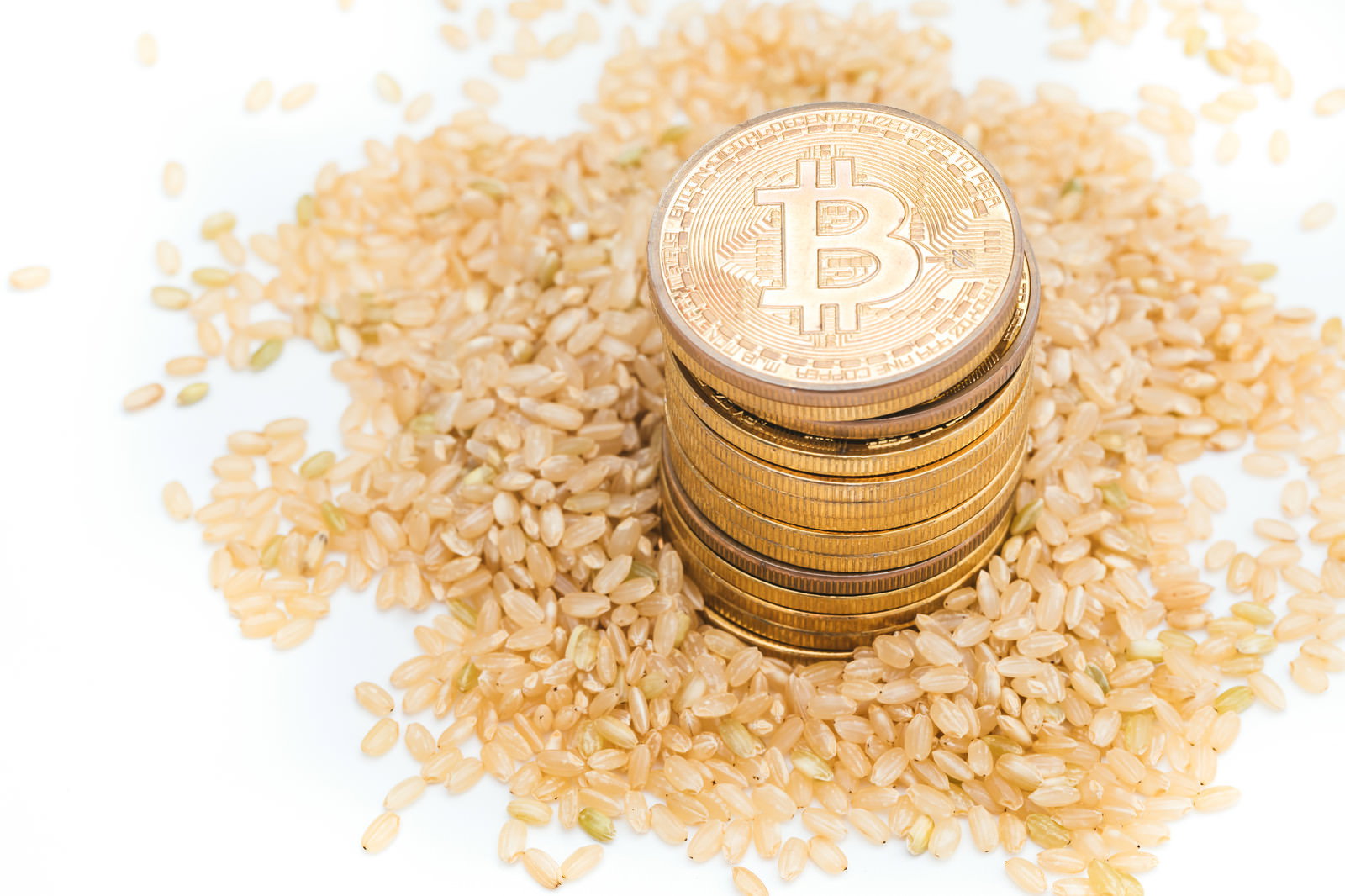 玄米の上に積み重ねられた金色のビットコインコイン